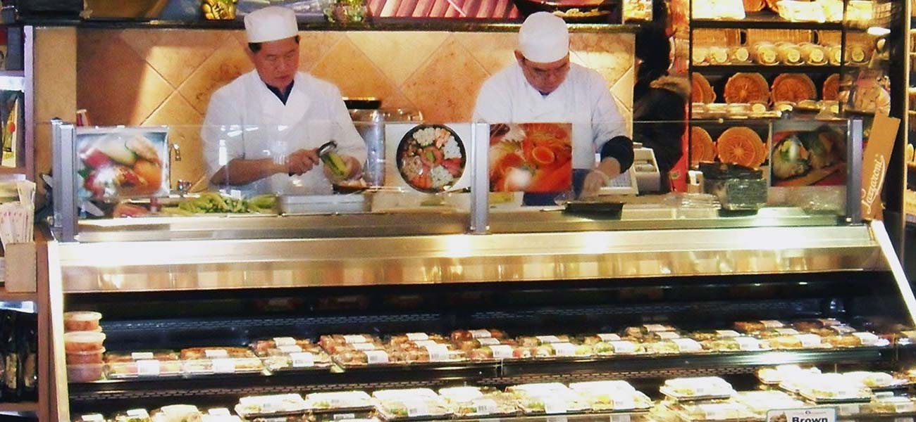 Two sushi chefs preparing sushi rolls