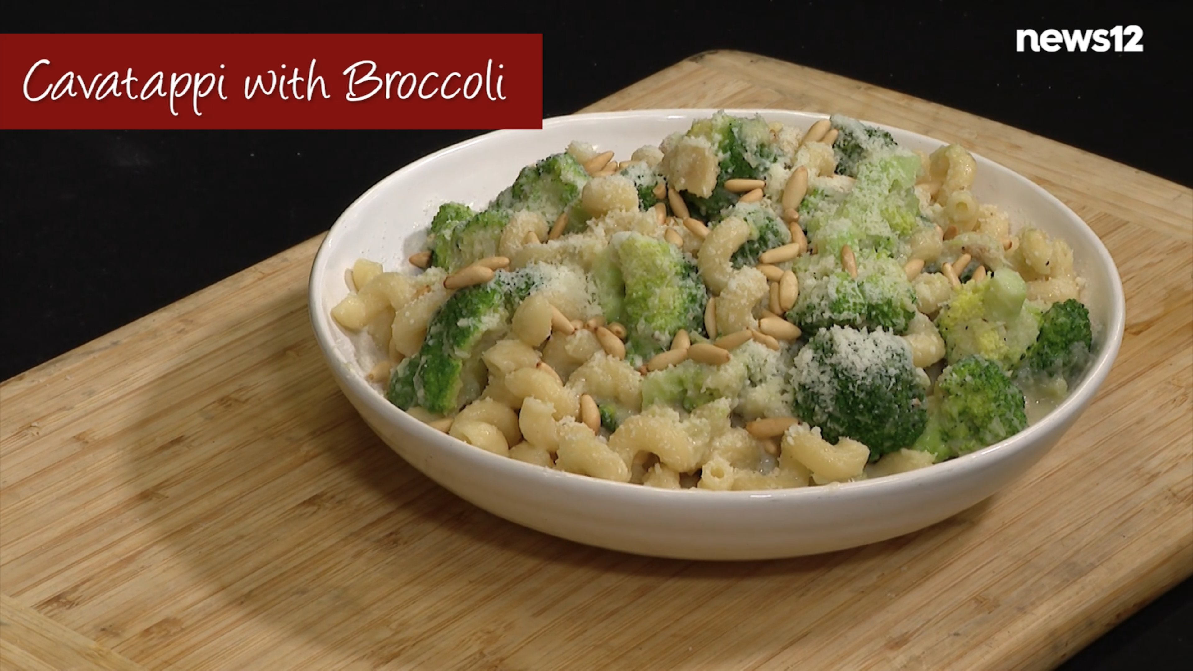 Cavatappi pasta with broccoli in a white bowl set on a cutting board