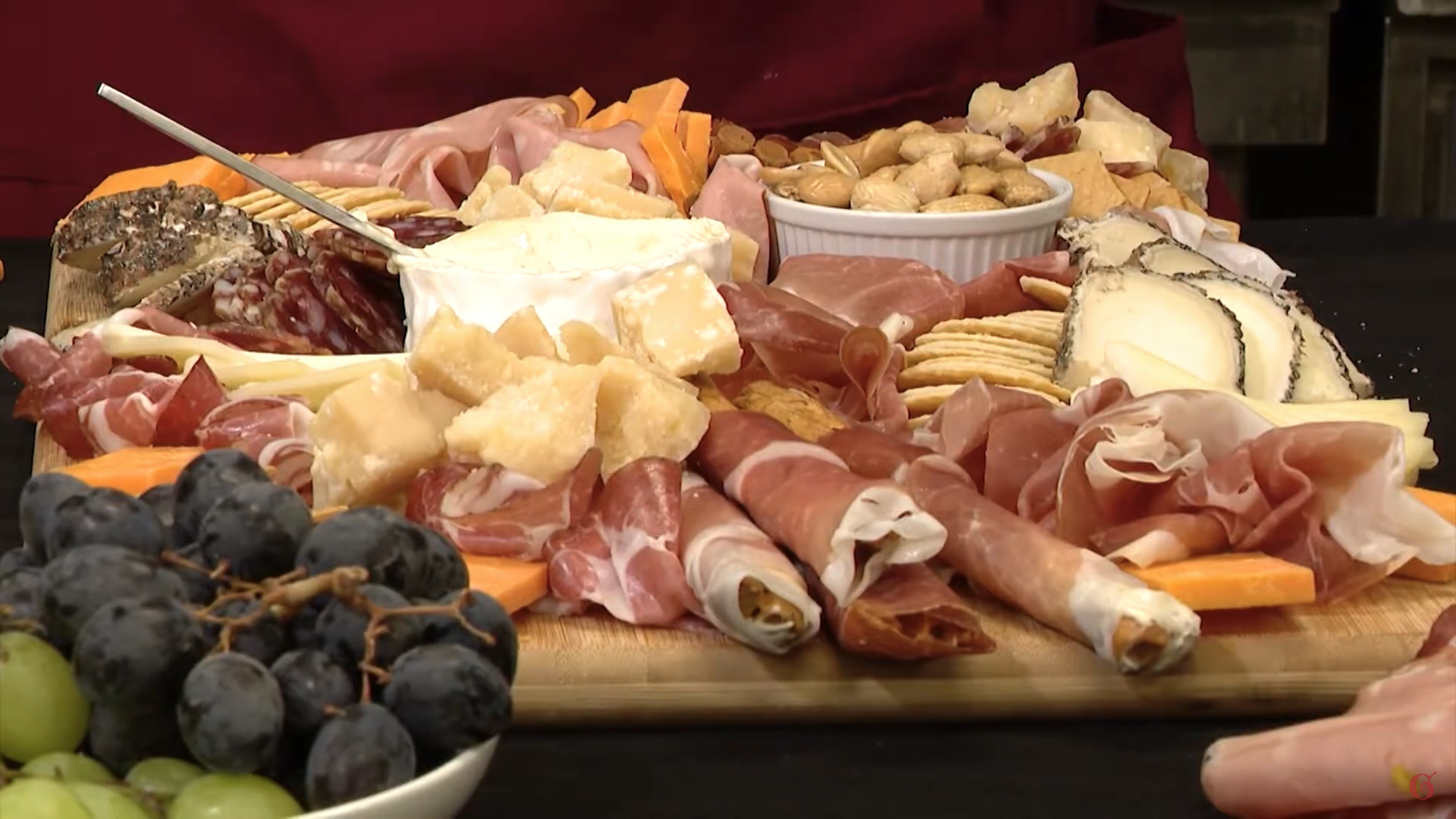 Assorted meats cheeses and fruits on a wood cutting board