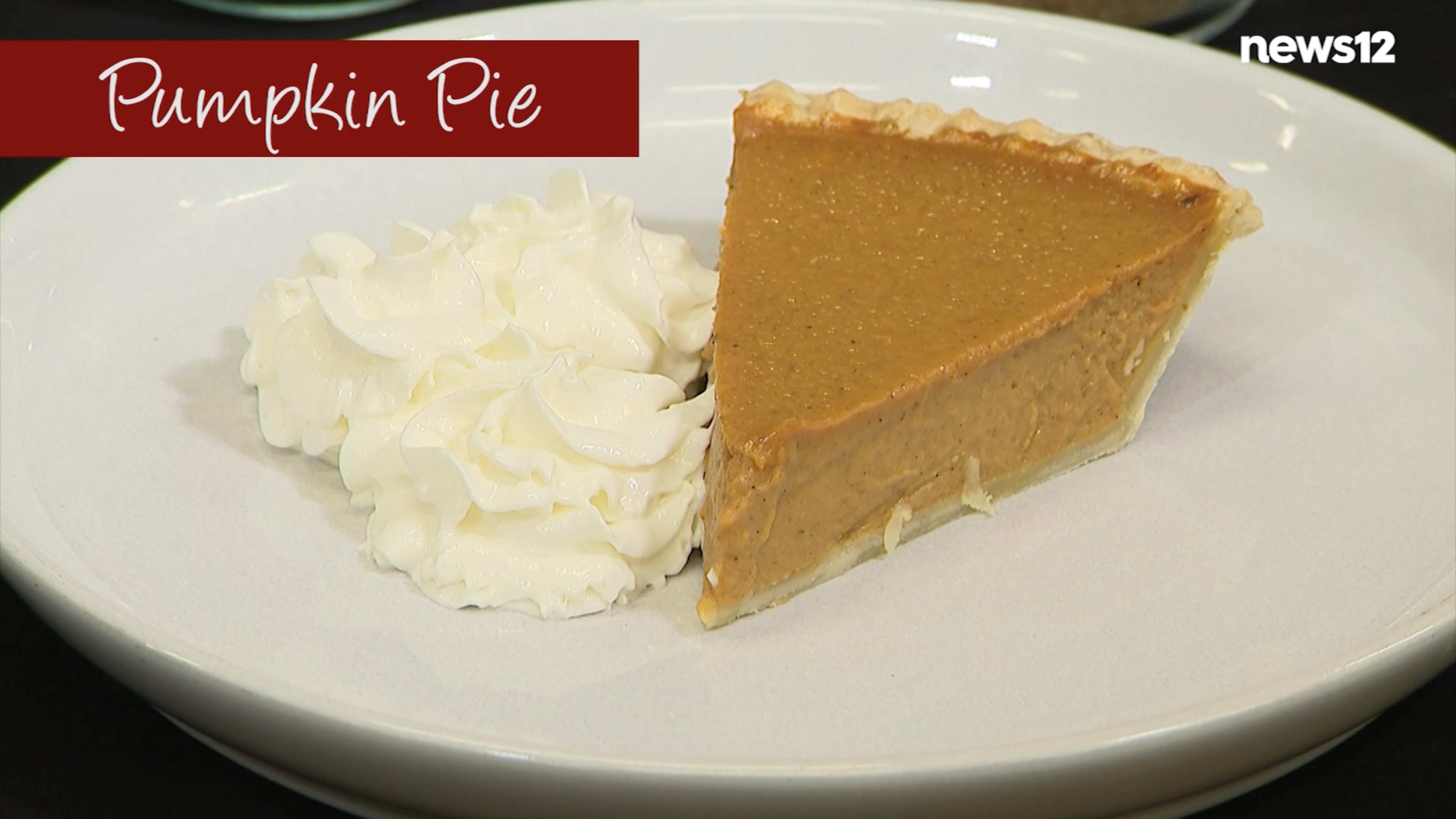 A slice of pumpkin pie on a white plate with a dollop of whipped cream next to it