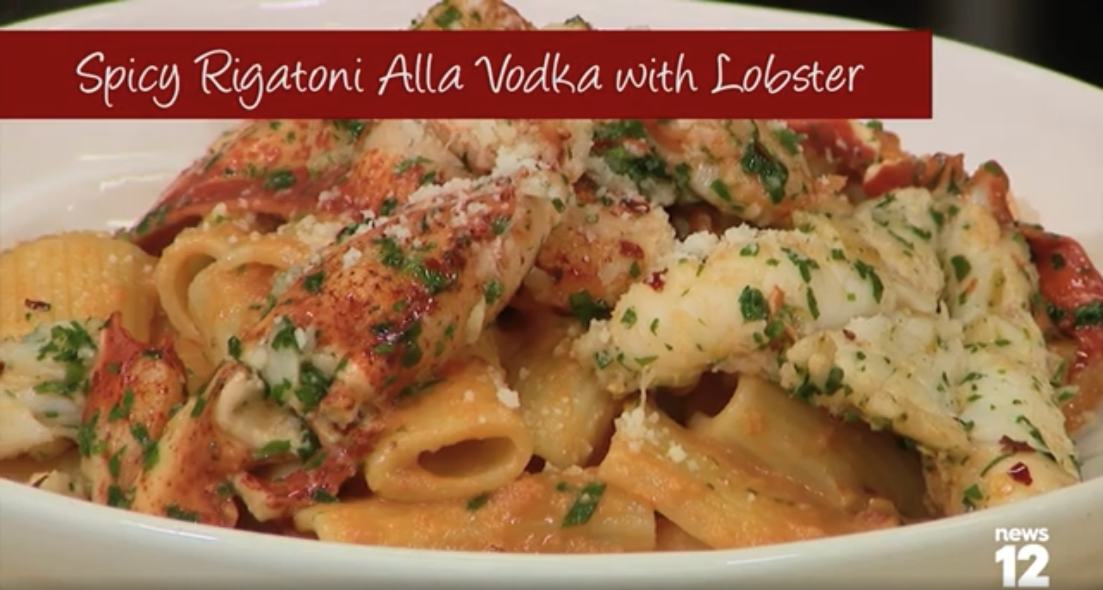 Rigatoni pasta in sauce topped with chunks of lobster