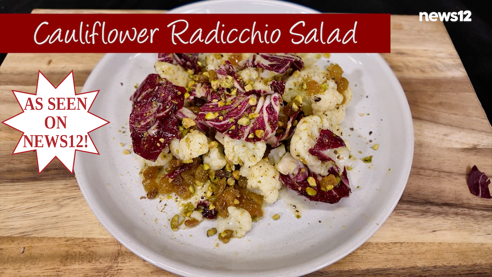 Cauliflower radicchio salad on a white plate set on a wood cutting board.