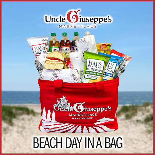 Red insulated bag filled with wrapped sandwiches and chips and drinks with "Beach day in a bag" written on it with the Uncle Giuseppe's logo