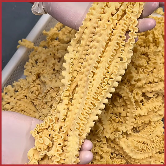Fresh Mafalda pasta in workers gloved hands